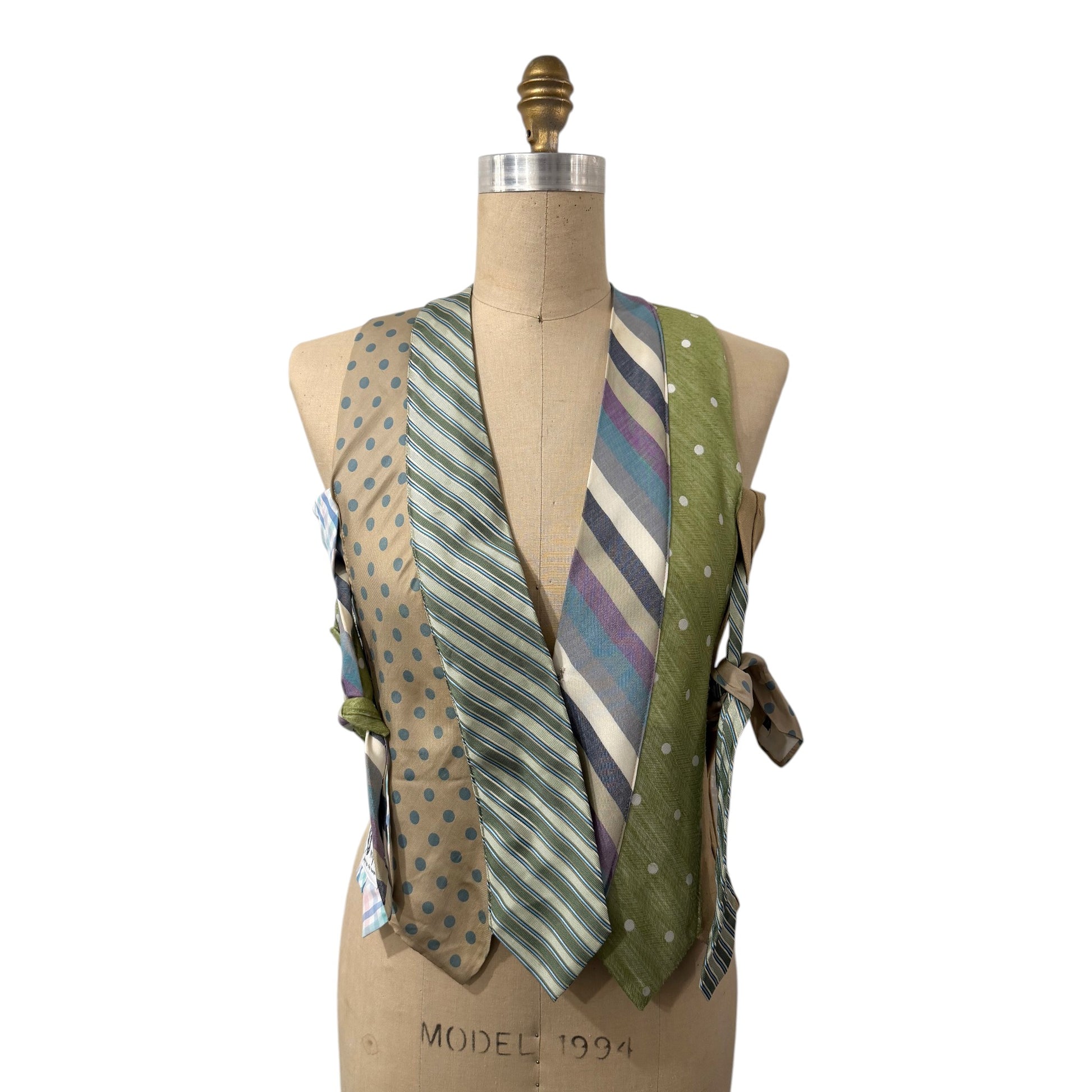 0 mph upcycled necktie vest in sage green, tan, and blue with polka dot and stripe patterns on a dress form.